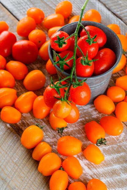 Tomates dans un mini seau plat posé sur une table en bois