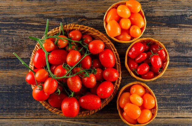 Tomates dans des paniers en osier sur une table en bois. pose à plat.