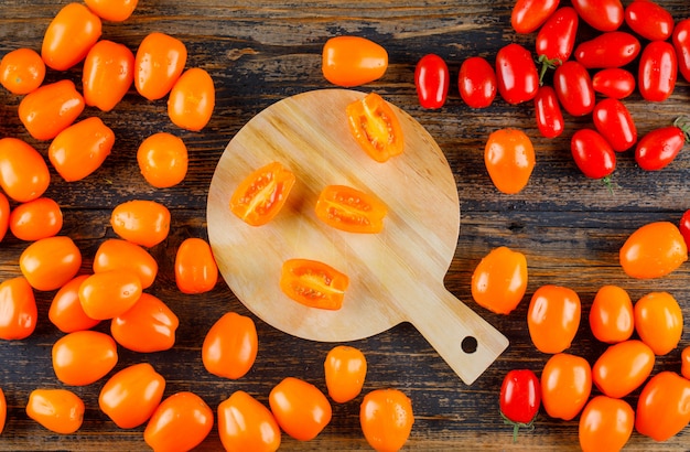 Tomates éparpillées sur planche de bois et à découper. pose à plat.