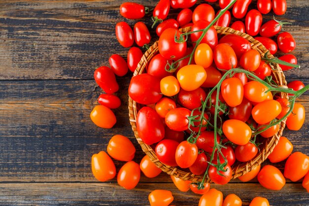 Tomates fraîches dans un panier en osier plat poser sur une table en bois