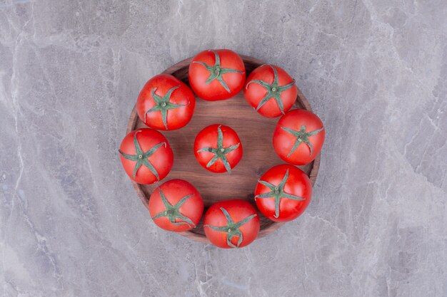 Tomates isolées dans un plateau en bois sur le marbre