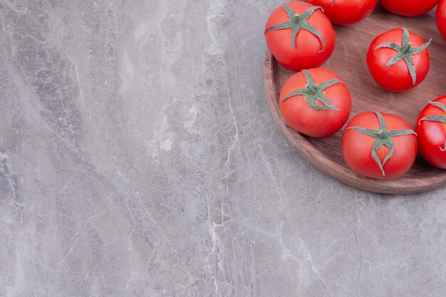 Tomates isolées dans un plateau en bois sur le marbre