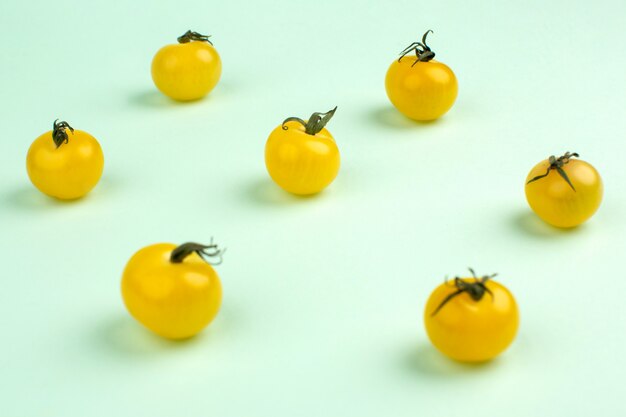 Tomates mûres fraîches jaunes peu isolées sur le vert de l'eau