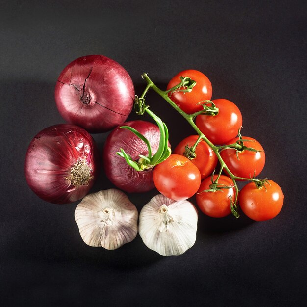 Les tomates, les oignons et l'ail sont isolés sur un fond noir