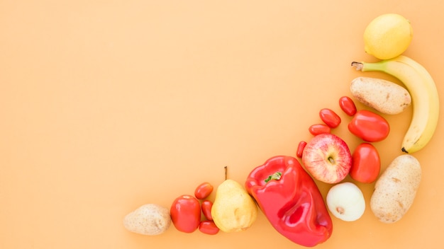 Tomates; patates; poires; banane; pomme et citron vert sur fond beige