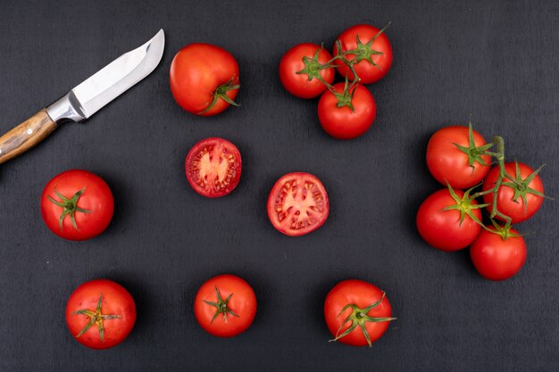 Tomates pleines et demi et près du couteau sur une surface noire