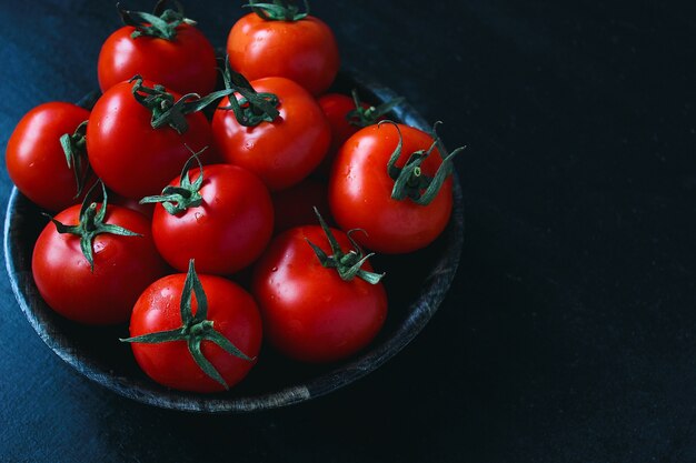 Tomates rouges biologiques fraîches en plaque noire, gros plan, concept santé, vue de dessus