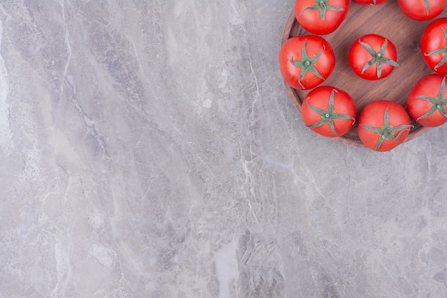 Tomates rouges isolés dans une assiette en bois