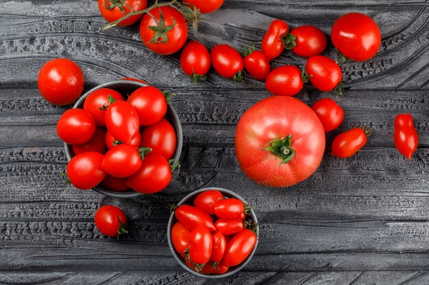 Tomates rouges en mini seaux sur mur en bois gris, vue de dessus.