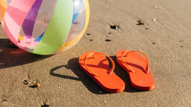 Tongs et ballon gonflable dans le sable à la plage