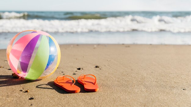 Tongs et ballon gonflable dans le sable à la plage