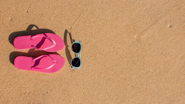 Tongs et lunettes de soleil sur le sable