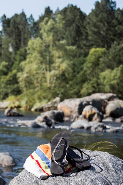 Tongs et une serviette sur la pierre près de l&#39;eau