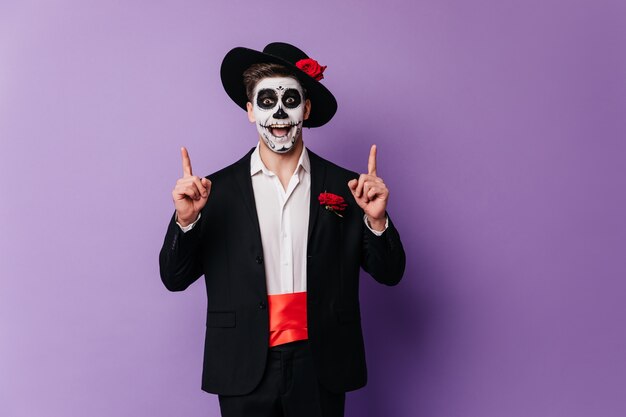 Étonné beau mec en tenue mexicaine se détendre à la fête. Photo d'Halloween d'un homme émotionnel en tenue de zombie.
