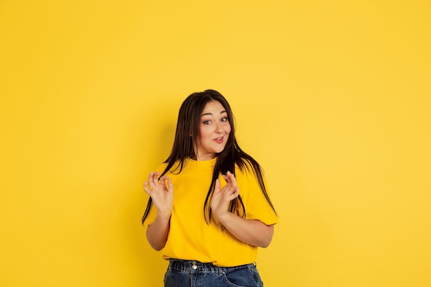 Étonné, demandé. Portrait de femme caucasienne isolé sur mur jaune. Beau modèle femme brune en tenue décontractée. Concept d'émotions humaines, expression faciale, ventes, copyspace.