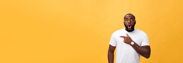 Étonné jeune hipster afro-américain portant un t-shirt blanc tenant la main dans un geste surpris