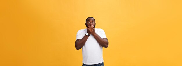 Étonné jeune hipster afro-américain portant un t-shirt blanc tenant la main dans un geste surpris