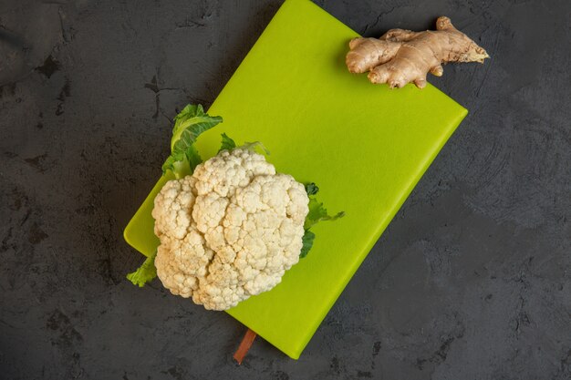 Top chou-fleur et gingembre sur une planche à découper verte sur dark