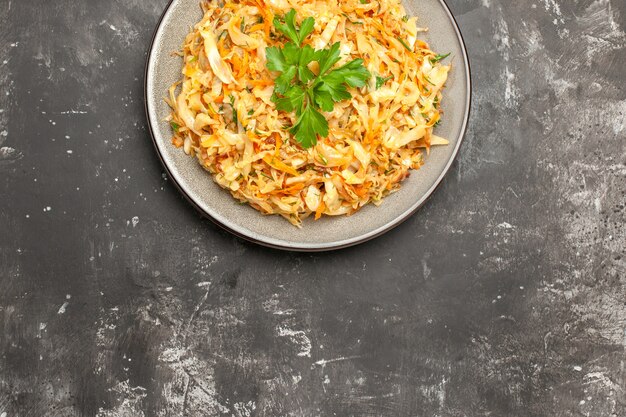 Top close-up view chou assiette blanche des carottes appétissantes herbes de chou sur la table