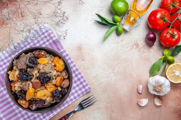 Top close-up view pilaf pilaf aux fruits secs sur la nappe tomates ail huile citron fourchette