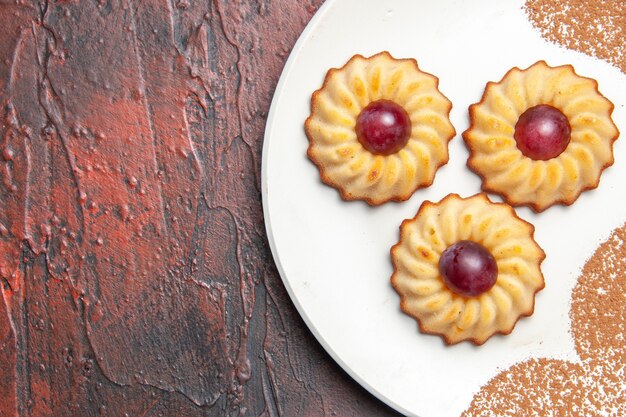 Photo gratuite top close view délicieux petits cookies à l'intérieur de la plaque sur le gâteau de table sombre biscuit sucré