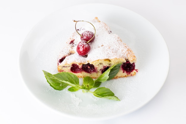 Top close view tranche de gâteau aux cerises délicieux et délicieux à l'intérieur de la plaque blanche sur le fond blanc gâteau biscuit pâte à sucre sucré cuire au four