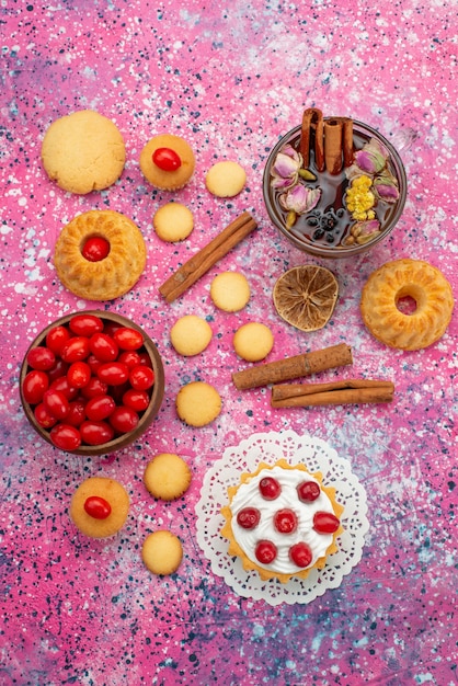 Top gâteau à la crème vue lointaine avec des canneberges rouges fraîches avec des biscuits à la cannelle et du thé sur le bureau lumineux biscuit sweet fruit berry