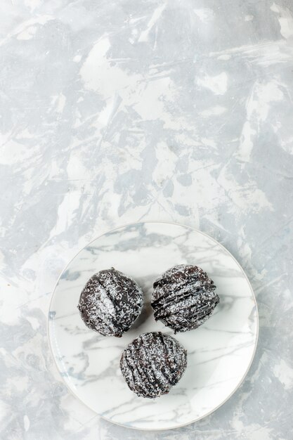 Top vue lointaine de délicieuses boules de chocolat rondes gâteaux formés avec du glaçage sur un bureau blanc clair cuire un gâteau au chocolat tarte au sucre
