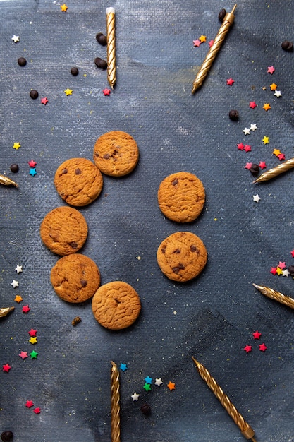 Photo gratuite top vue lointaine délicieux biscuits au chocolat avec des bougies sur le bureau gris foncé biscuit biscuit thé sucré sucre