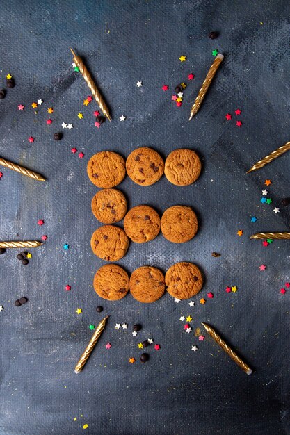 Top vue lointaine délicieux cookies au chocolat avec des bougies et des décorations sur le fond sombre biscuit biscuit thé sucré sucre