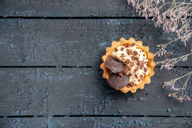 Top vue lointaine tarte avec branche de fleurs séchées au chocolat sur table en bois foncé