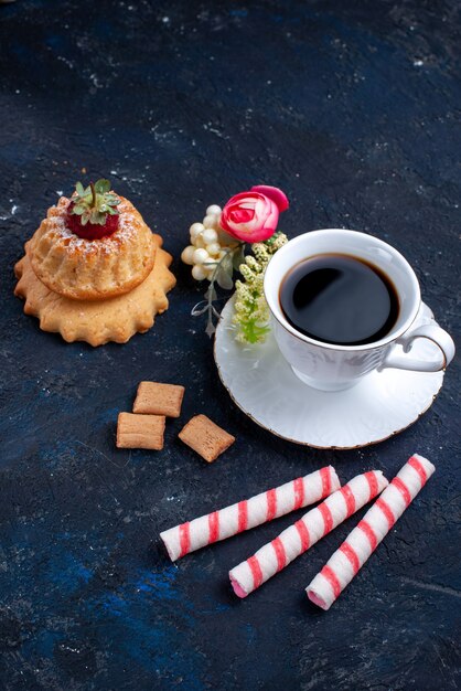 Top vue lointaine tasse de café avec des bonbons de bâton rose et un gâteau sur bleu