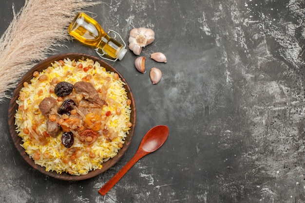 Top vue rapprochée de l'ail pilaf bouteille d'huile cuillère en bois un appétissant pilaf