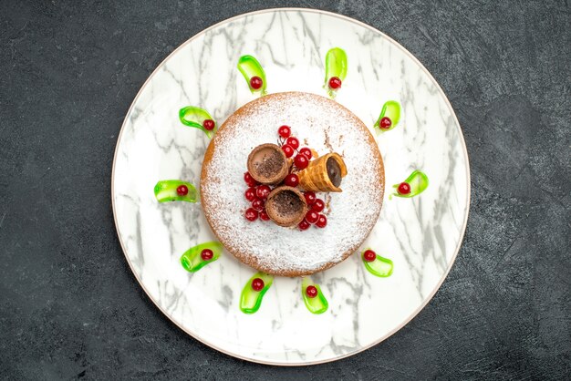 Top vue rapprochée d'une assiette à gâteau d'un gâteau appétissant avec des baies gaufres au sucre en poudre