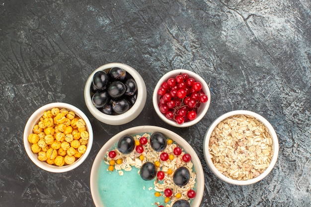 Photo gratuite top vue rapprochée de baies bols de bonbons jaunes à l'avoine, raisins et groseilles rouges