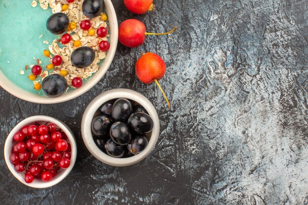 Top vue rapprochée baies groseilles rouges raisins noirs dans le bol de gruau de baies sur la plaque cerise