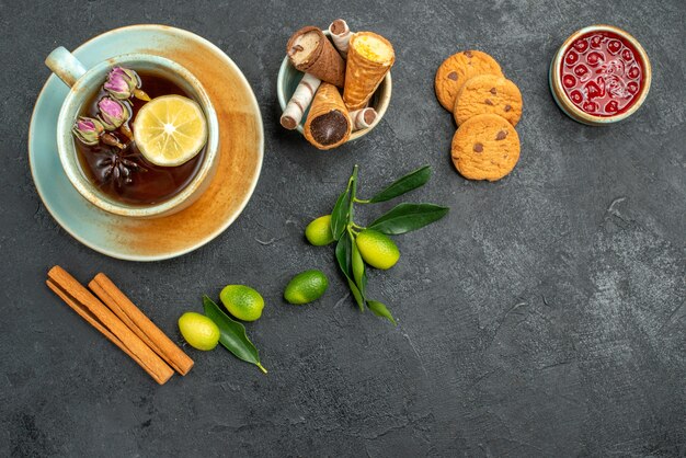 Top vue rapprochée bonbons gaufres dans un bol une tasse de biscuits à la cannelle confiture d'agrumes