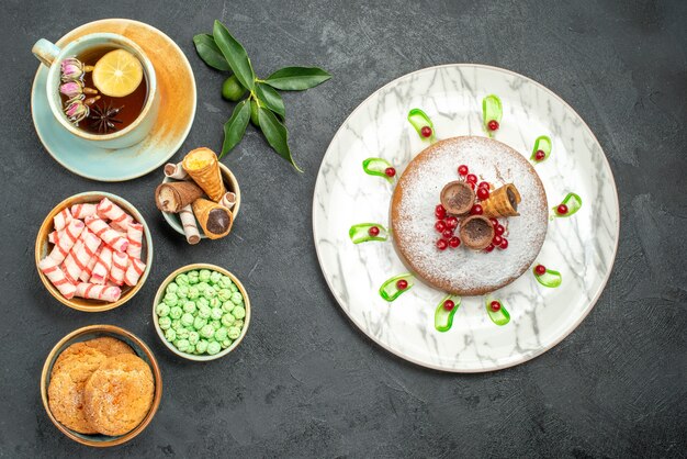 Top vue rapprochée des bonbons une tasse de biscuits au thé gaufres bonbons gâteau aux agrumes avec des baies