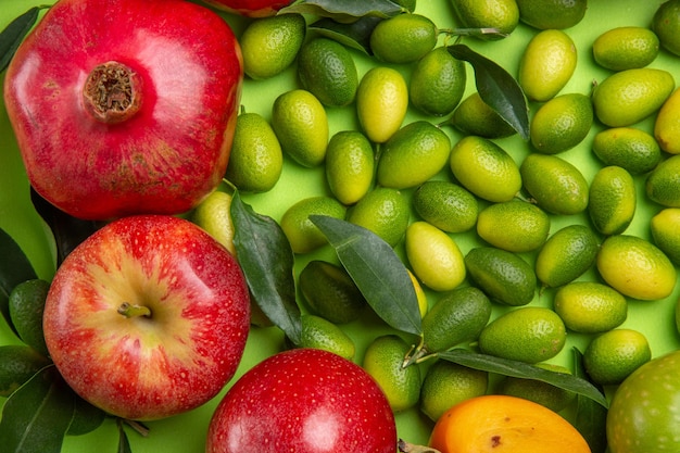 Top vue rapprochée fruits agrumes grenades pommes sur la table verte