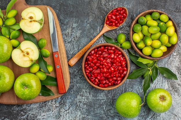 Top vue rapprochée fruits grenade cuillère pommes agrumes pommes couteau sur la planche