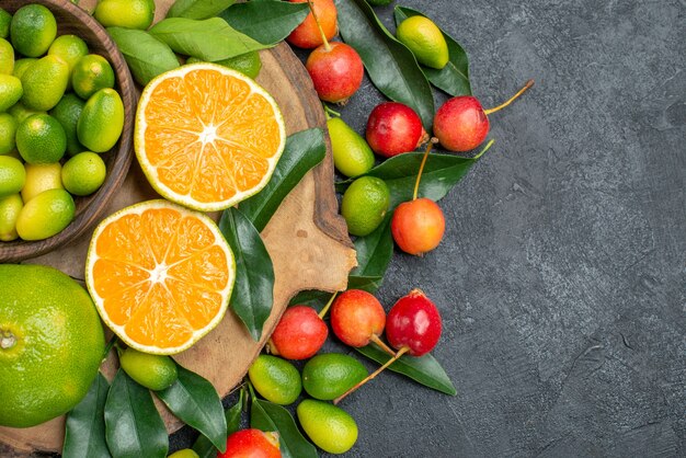 Top vue rapprochée fruits la planche à découper avec des agrumes avec des feuilles et des cerises