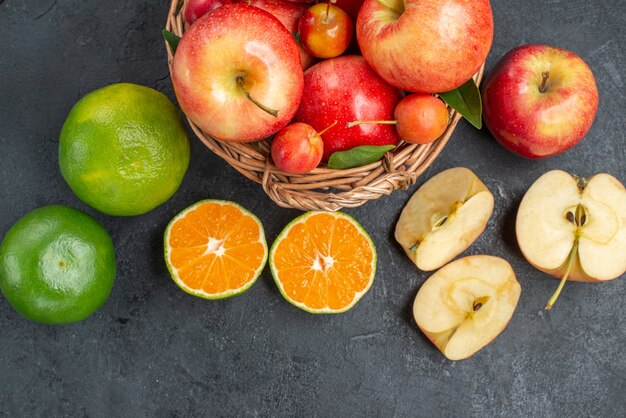 Top vue rapprochée fruits pommes et cerises dans le panier pommes agrumes