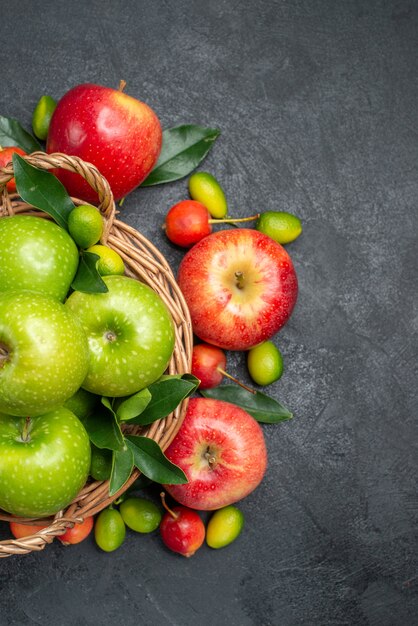 Top vue rapprochée fruits pommes rouges cerises agrumes autour du panier de pommes vertes