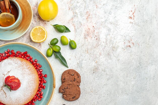 Top vue rapprochée gâteau assiette bleue de gâteau aux fraises biscuits agrumes sur la table