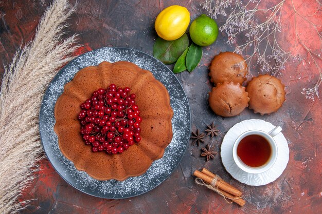 Top vue rapprochée gâteau aux cupcakes avec cupcakes aux groseilles rouges une tasse de thé à l'anis étoilé