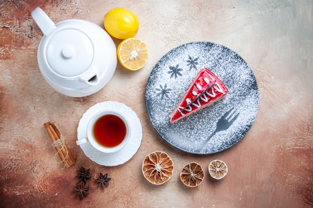 Top vue rapprochée d'un gâteau blanc tasse de thé un gâteau théière citron cannelle bâtons