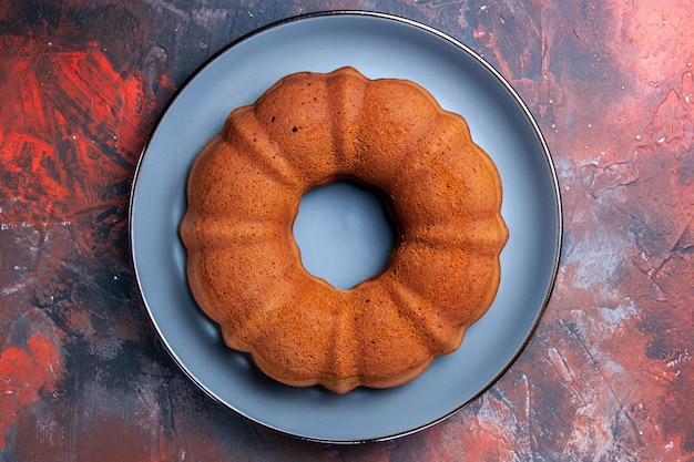 Top vue rapprochée gâteau un gâteau appétissant sur la plaque ronde bleue sur la table bleu-rouge