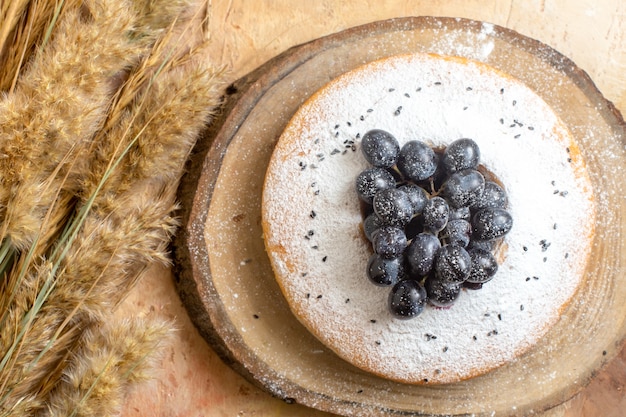 Top vue rapprochée d'un gâteau un gâteau avec des épillets de raisins noirs sur la table