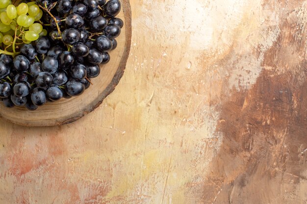 Top vue rapprochée des grappes de raisins de raisins noirs et verts sur la planche à découper en bois