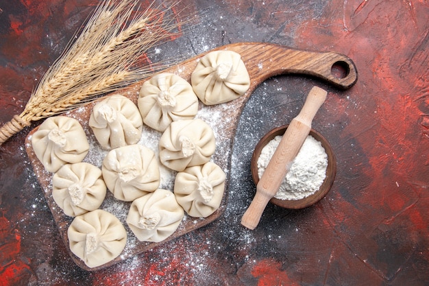 Top vue rapprochée khinkali khinkali sur la planche à découper épis de blé farine rouleau à pâtisserie